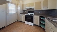 This single-story home offers a practical and comfortable layout across a well-organized floor plan. The main living area is a standout space, combining wood-look laminate flooring with plush carpeting, and is equipped with a ceiling fan and light kit. Multiple windows allow natural light to fill the room, while vertical blinds on a sliding door provide access and privacy. The kitchen is efficiently designed with ample white cabinetry extending to the ceiling, dark laminate countertops, and a textured tile backsplash. It includes a gas range with overhead ventilation, a double-basin sink beneath a window, a dishwasher, and a full-size refrigerator. Lazy Susan corner cabinets maximize storage in this well-equipped space. The bedrooms are carpeted and bright, each featuring sliding closet doors and windows with blinds that bring in natural light. One bedroom includes an additional open closet area, offering generous storage. The hallway connecting the rooms provides convenient access throughout the home. The bathroom is clean and functional, featuring a white vanity with under-sink storage and a mirrored medicine cabinet, tile-accented walls, durable vinyl flooring, and a full soaking tub with a shower surround and built-in shelving.