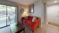 Located at 12520 Gayton Rd in Henrico, Virginia, this single-floor residence offers a well-organized layout with a comfortable and functional flow throughout. The living room serves as a central gathering space, featuring a tiled fireplace, wall-mounted television, and a sliding glass door that opens onto a private deck overlooking lush, tree-lined surroundings — filling the room with natural light and pleasant outdoor views. Adjacent to the living area, the dining space accommodates a round table with seating for four, accented by a ceiling fan with integrated lighting and warm, neutral-toned carpeting. The galley-style kitchen is efficiently designed with ample warm wood cabinetry, dark granite countertops, a double stainless steel sink, tile flooring, and black appliances including an electric range and built-in microwave. Two bedrooms provide comfortable retreats, each featuring plush carpeting, generous natural light from sizable windows, and access to closet space. The primary bedroom connects to a private bathroom, while a second full bathroom serves the remainder of the home. Both bathrooms are finished with tile flooring and oak vanities with light countertops. The overall ambiance of the home is warm and inviting, with a cohesive neutral palette and tasteful decorative touches throughout.