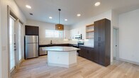 Located at 325 Melba St in Dallas's 75208 zip code, this single-story home showcases a contemporary design with a clean, modern aesthetic carried consistently throughout. Light wood-toned flooring flows seamlessly across the open-concept living and kitchen areas, enhancing the sense of continuity and space.

The kitchen serves as a central highlight, featuring a two-tone cabinetry scheme that pairs crisp white upper cabinets with rich dark lower cabinets. A marble-style tile backsplash adds elegance, while open wood shelving introduces a warm, organic contrast. A central island with a quartz-style countertop anchors the space beneath a distinctive woven pendant light fixture. Stainless steel appliances, including a refrigerator, range, and microwave, complete the functional design. French doors and multiple windows bring in abundant natural light.

The bathrooms reflect the same attention to detail. One features a tub-shower combination with large-format marble-look tile and matte black hardware. The primary bath includes a walk-in shower with built-in shelving, a wood-toned vanity, decorative pendant lighting, a herringbone accent wall, and direct access to a walk-in closet. Additional rooms are bright and versatile, with recessed lighting and generous window placement.