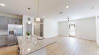 Located at 3755 E McKinney St in Denton, TX, this single-story, 3-bedroom, 2-bathroom home offers a clean, modern design with thoughtful finishes throughout. The open-concept kitchen and living area serves as the heart of the home, featuring light hardwood-style flooring, a ceiling fan, and a glass door that fills the space with natural light. The kitchen is well-appointed with gray shaker-style cabinetry, a granite-topped island with pendant lighting, stainless steel appliances including a refrigerator, range, microwave, and dishwasher, and a crisp white tile backsplash. The bedrooms are carpeted and generously sized, each equipped with ceiling fans. The primary bedroom includes access to a walk-in closet outfitted with dual hanging rods and built-in shelving, as well as an en-suite bathroom. An additional bedroom features hardwood-style flooring and direct exterior door access. The bathrooms are finished with marble-look tile surrounds and matte black fixtures. With four closets total, storage is plentiful throughout. The home's bright, neutral palette and consistent finishes create a cohesive and inviting atmosphere from room to room.