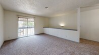 Located at 5808 E 71st St in Tulsa, Oklahoma, this one-bedroom, one-bathroom unit offers a thoughtfully arranged split-level layout connected by an interior staircase. The living area is carpeted and bathed in natural light streaming through large sliding glass doors that open to a private balcony, offering pleasant outdoor views. A built-in wall shelf adds a functional architectural detail to the living space, while a ceiling fan provides year-round comfort. A pass-through window connects the living area to the kitchen, which features gray cabinetry and includes essential appliances. The bedroom is a comfortable, carpeted retreat with a natural light source via a window and direct access to a dedicated walk-in closet equipped with a hanging rod and built-in shelving — providing generous storage. The full bathroom is finished with light wood-look flooring, white tile surround in the tub-shower combination, a vanity with a speckled countertop, and a large mirror. Textured ceilings are present throughout the unit, lending a consistent finish across all rooms. This well-organized unit balances functional living spaces with practical storage solutions in a convenient Tulsa location.