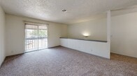 Located at 5808 E 71st St in Tulsa, Oklahoma, this one-bedroom, one-bathroom unit offers a thoughtfully arranged split-level layout connected by an interior staircase. The living area is carpeted and bathed in natural light streaming through large sliding glass doors that open to a private balcony, offering pleasant outdoor views. A built-in wall shelf adds a functional architectural detail to the living space, while a ceiling fan provides year-round comfort. A pass-through window connects the living area to the kitchen, which features gray cabinetry and includes essential appliances. The bedroom is a comfortable, carpeted retreat with a natural light source via a window and direct access to a dedicated walk-in closet equipped with a hanging rod and built-in shelving — providing generous storage. The full bathroom is finished with light wood-look flooring, white tile surround in the tub-shower combination, a vanity with a speckled countertop, and a large mirror. Textured ceilings are present throughout the unit, lending a consistent finish across all rooms. This well-organized unit balances functional living spaces with practical storage solutions in a convenient Tulsa location.