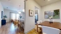 Located in Northlake, TX, this thoughtfully designed one-bedroom, two-bathroom residence offers a cohesive open-concept floor plan that maximizes every square foot. The kitchen serves as a central hub, showcasing granite countertops, a spacious island with bar seating, taupe cabinetry, stainless steel appliances, and stylish globe pendant lighting — all flowing seamlessly onto light hardwood floors. An arched passageway connects the kitchen to a dedicated dining room, which provides an intimate setting accented by clean white walls and curated wall art. The adjacent living room benefits from large windows and a private balcony access, filling the space with abundant natural light and outdoor views. The primary bedroom is a comfortable retreat featuring a soft accent wall, plush carpet, and a well-sized walk-in closet with built-in shelving and hanging rods. Two full bathrooms serve the residence, one featuring a soaking tub framed by elegant marble-style tile and brushed gold fixtures. The overall ambiance is modern and warm, with a neutral palette, vaulted ceiling details in select areas, and quality finishes throughout that create an inviting, functional living environment.