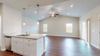 This two-story home is thoughtfully laid out across two floors, with the larger main level housing the primary living and kitchen areas, and the upper level dedicated largely to bedrooms and additional bathrooms. The main floor features hardwood-style flooring throughout, lending a clean and cohesive look to the open-concept kitchen and living room. The kitchen is well-equipped with stainless steel appliances, including a range, microwave, refrigerator, and dishwasher, complemented by white shaker cabinetry and light granite countertops. A kitchen island with a built-in sink and pendant lighting adds both functionality and style. The living room is bright and airy, with a sliding glass door providing direct access to the outdoors and allowing natural light to fill the space.

Upstairs, plush carpeting runs through the hallway and bedrooms. The primary bedroom includes a ceiling fan and direct access to a private bathroom and walk-in closet with wire shelving. Additional bedrooms are generously sized with their own closet access. A half bathroom on the main floor features a pedestal sink, while the upper-level bathrooms serve the remaining bedrooms. A dedicated laundry area and four closets add to the home's practical storage capacity.