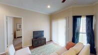 This single-floor, 2-bedroom, 1-bathroom residence offers a thoughtfully designed layout that maximizes comfort and functionality. The living room serves as the heart of the home, featuring warm hardwood-style flooring, crown molding, a ceiling fan, and a textured ceiling. A large sliding glass door with vertical blinds fills the space with natural light and provides direct access to an outdoor area, enhancing the open feel of the room.

The kitchen is well-equipped with rich dark cabinetry, granite-style countertops, black appliances including a range, refrigerator, and dishwasher, and durable hardwood-style flooring. A breakfast bar adds additional counter space and casual dining options.

Both bedrooms feature plush carpeting and ceiling fans, creating a cozy and restful environment. The primary bedroom includes a closet with built-in storage and a window that brings in natural light. The second bedroom also benefits from a bright window and wall-mounted shelving for added storage.

The bathroom mirrors the kitchen's design aesthetic with dark cabinetry, granite-style countertops, and a large vanity mirror. The entryway includes mirrored sliding closet doors, adding depth and practicality to the space. Throughout, neutral warm tones create a cohesive and inviting ambiance.