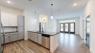 Located at 1900 Olevia St in Jacksonville, FL, this well-appointed 2-bedroom, 2-bathroom unit is spread across a single floor, offering a thoughtfully designed layout with modern finishes throughout. Wood-look plank flooring runs seamlessly through the open living areas, creating a cohesive and contemporary feel.

The open-concept kitchen is a standout feature, boasting two-toned cabinetry with white upper cabinets and gray lower cabinets, a white subway tile backsplash, dark stone countertops, a breakfast bar peninsula with pendant lighting, and stainless steel appliances. The adjacent living area is bright and airy, with tall ceilings, large French doors topped with transom windows, and ample natural light.

Both bedrooms are well-sized, with the primary bedroom offering a ceiling fan and generous windows with outdoor views. Each bedroom is served by its own dedicated walk-in closet fitted with multi-level wire shelving systems for organized storage.

The bathrooms are elegantly finished, featuring gray vanity cabinetry with granite countertops, black matte fixtures, and white subway tile surrounds. The primary bath includes a glass-enclosed walk-in shower, while the secondary bath offers a full soaking tub and shower combination. Clean white walls and elevated ceiling heights enhance the sense of openness throughout the entire space.
