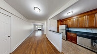 This single-floor unit at Greenwich Close offers a thoughtfully designed layout that maximizes functionality and comfort. Rich hardwood flooring extends throughout the main living areas, lending warmth and a cohesive aesthetic to the space. The open living area is generously proportioned, with neutral white walls and multiple windows that invite natural light and provide pleasant outdoor views of surrounding greenery.

The semi-open kitchen is defined by a peninsula with a dark granite-style countertop, creating a natural division from the living space while maintaining an open feel. Rich, warm-toned wooden cabinetry with raised-panel detailing offers ample storage, complemented by dark countertops and stainless steel appliances, including a refrigerator and dishwasher. The kitchen is finished with neutral tile flooring.

The bedroom is a comfortable, well-proportioned room featuring the same warm hardwood flooring, a large window with outdoor views, and a double-door closet providing substantial storage. The clean white walls create a bright, restful environment.

The bathroom features a full tub-shower combination enclosed by white subway tile, paired with a white vanity and wood-look tile flooring, resulting in a clean and classic finish throughout.