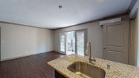 Located at 1019 Everett Ave in Louisville, Kentucky, this single-floor unit offers a well-designed layout that balances functionality and modern style throughout. The open living area is anchored by rich, dark hardwood flooring that extends seamlessly through the main spaces, complemented by neutral-toned walls and crown molding details. French doors flood the living area with natural light and provide direct access to a private balcony, offering outdoor views of the surrounding neighborhood.

The kitchen is thoughtfully appointed with dark espresso cabinetry, granite countertops, a subway tile backsplash, and a full suite of stainless steel appliances, including a refrigerator, range, and microwave. A kitchen island with an undermount sink adds prep space and a natural transition into the living area. A large, dark-stained armoire-style storage unit provides additional storage in the main living space.

The bathroom features granite countertops with a dark vanity, tile flooring, and a tub-shower combination with classic white subway tile accented by a decorative mosaic tile inset. A dedicated laundry area with a stacked washer and dryer adds everyday convenience. A wall-mounted mini-split unit provides climate control throughout the space. Overall, the unit presents a clean, contemporary aesthetic with practical amenities throughout.