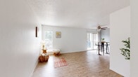 This well-appointed single-floor residence offers a thoughtfully designed layout that balances comfort and functionality. The open living and dining area is a welcoming centerpiece, featuring warm wood-look flooring, crisp white walls, and a textured ceiling. Abundant natural light pours in through multiple windows and a sliding glass door that leads to an outdoor space, creating a bright and airy atmosphere. A ceiling fan adds to the comfort of the room, while the seamless flow between the living and dining zones makes the space feel generous and versatile.

The galley-style kitchen is efficiently arranged with white cabinetry, a double-basin stainless steel sink, and a stylish mosaic tile backsplash. Black appliances, including a range and dishwasher, provide a clean contrast against the light countertops and wood-look flooring underfoot.

The bedrooms offer carpeted flooring and ceiling fans, with natural light filtering in through windows fitted with blinds. One bedroom features a spacious walk-in closet with dual clothing rods and shelving on both sides, providing ample storage. The bathroom is clean and functional, complete with a full tub and shower combination, a single vanity, and wood-look flooring. Overall, this residence presents a comfortable and practical living environment with a light, neutral aesthetic throughout.