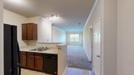 Located at 114 St Thomas St in Rock Hill, SC, this two-bedroom, three-bathroom residence offers a well-organized single-floor layout designed for comfortable everyday living. The kitchen is outfitted with rich, dark wood cabinetry, light granite-style countertops, a double stainless steel sink, and black appliances including a refrigerator, microwave, and range. A breakfast bar-style peninsula separates the kitchen from the adjoining living area, which features plush carpeting and crown molding that adds a refined touch to the space. Tile flooring runs through the kitchen and bathrooms, providing a clean, durable transition between areas. The primary bedroom is generously sized, featuring carpet flooring, a ceiling fan, and a window that brings in natural light. The second bedroom also offers carpeted floors, natural light through a window, and access to a closet. The three bathrooms are consistently appointed with dark wood vanities, light countertops, lighted mirrors, and tub-shower combinations. A hallway connects the main living spaces to the bedrooms and bathrooms, contributing to the unit's efficient flow. Two closets provide ample storage throughout the residence. Neutral, warm-toned walls throughout create a cohesive and inviting atmosphere.