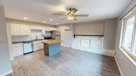 Located at 811 E Red Bud Rd in Knoxville, Tennessee, this well-appointed one-bedroom, one-bathroom home offers a thoughtfully designed single-floor layout. The open-concept kitchen and living area serves as the heart of the home, featuring white shaker cabinetry, a subway tile backsplash, dark countertops, and a full suite of stainless steel appliances including a dishwasher, electric range, and refrigerator. A freestanding kitchen island with a warm butcher block top provides additional prep and dining space. A wall-mounted mini-split unit ensures efficient climate control throughout. The living area is anchored by a charming white-painted brick fireplace with built-in shelving, and a ceiling fan adds to the comfortable ambiance. Light wood-tone flooring flows seamlessly through the main living spaces. The bedroom offers a cozy, functional retreat with a wall-mounted mini-split, a sliding window overlooking a deck and wooded surroundings, and access to an exterior door. The bathroom features a full tub/shower combination with classic white subway tile surround. Darker hardwood-style flooring grounds the bedroom and bathroom areas, providing a pleasant contrast throughout the home.
