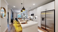 Located at 5672 Peachtree Pkwy in Peachtree Corners, GA, this thoughtfully designed 2-bedroom, 2-bathroom residence offers a smart, efficient layout across a single floor. The open-concept kitchen is a standout feature, showcasing white shaker cabinetry, quartz countertops, stainless steel appliances, and a large center island with pendant lighting and seating — seamlessly connecting to the dining area and living room. The living space is characterized by crown molding, hardwood-style flooring, and an artfully styled ambiance with a decorative ceiling and statement chandelier. Natural light flows in through multiple windows dressed with layered curtains. The primary bedroom offers a serene retreat with a bold accent wall, plush carpeting, and a dedicated walk-in closet with built-in shelving. The second bedroom is equally comfortable with natural light and soft carpeting. Both bathrooms are finished with white vanities, quartz countertops, matte black fixtures, and hardwood-style flooring. A conveniently located in-unit washer and dryer add practical everyday comfort. The space combines contemporary design with a warm, livable character throughout.