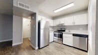 This single-floor unit offers a thoughtfully updated interior with a cohesive, modern aesthetic throughout. The kitchen is a standout feature, showcasing crisp white shaker-style cabinetry, light stone-look countertops, and a full suite of stainless steel appliances including a refrigerator, electric range, and dishwasher. A stainless steel sink with a modern faucet and a window providing natural light complete this functional and stylish space. Wood-look luxury vinyl plank flooring runs throughout the kitchen and extends into the living areas, offering both durability and visual continuity. The living spaces are open and versatile, characterized by neutral gray walls, clean white baseboards, and a textured popcorn ceiling. Multiple electrical outlets are positioned throughout for convenience. The bathroom is well-appointed with white shaker-style vanity cabinetry, a speckled stone-look countertop, an undermount sink, and a full-size tub and shower combination. Wood-look flooring continues into the bathroom, maintaining a unified design language. A hallway connects the rooms, adding a sense of flow to the layout. Overall, the space presents a clean, move-in-ready environment with updated finishes and a practical, functional design.