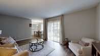 Located at 37 Treeview Drive in Stonecrest, Georgia, this two-bedroom, one-bathroom single-floor residence offers a thoughtfully laid-out living space with a warm, neutral aesthetic throughout. The living room serves as the heart of the home, featuring hardwood-style flooring, soft neutral walls, and a sliding glass door dressed with sheer curtains that fills the area with natural light and provides outdoor views. The space flows naturally into a dedicated dining area, illuminated by a pendant light fixture and a large window, creating an inviting setting for meals. The kitchen is efficiently designed with white cabinetry, dark speckled countertops, a breakfast bar peninsula, and wood-style flooring that ties the common areas together cohesively. Both bedrooms are carpeted for comfort, each offering a closet for storage. The spacious primary bedroom features a walk-in style closet and direct access to the hallway connecting the rest of the home. The bathroom is appointed with a wide vanity topped with dark granite-style counters, a large mirror, and modern light fixtures. Three additional closets throughout the home provide ample storage. The overall ambiance is clean, bright, and move-in ready, offering a practical and comfortable layout ideal for everyday living.