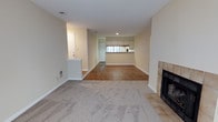 Located at 450 Johnny Mercer Blvd in Savannah, Georgia, this single-floor residence offers a thoughtfully laid-out interior with a warm, neutral palette throughout. The main living area is anchored by a tile-surround fireplace and features plush carpeting that transitions to hardwood-style flooring as you move through the space. A half-wall partition adds subtle architectural definition, separating the entryway from the living room while maintaining an open feel. Large windows at the far end of the living area flood the space with natural light, creating a bright and inviting atmosphere. The kitchen is well-appointed with ample white cabinetry accented by wood trim, a double sink, a coil-burner range, a dishwasher, and a refrigerator. A pass-through window connects the kitchen to the adjacent dining or living area, enhancing the open-concept flow. A dedicated sunroom or bonus room at the rear of the home is surrounded by a bank of windows on multiple walls, allowing abundant natural light and views of the surrounding greenery. A ceiling fan keeps the room comfortable year-round. Hardwood flooring in this space adds warmth and character. The overall ambiance is comfortable and functional, offering a livable layout ideal for everyday life in coastal Savannah.