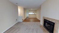 Located at 450 Johnny Mercer Blvd in Savannah, Georgia, this single-floor residence offers a thoughtfully laid-out interior with a warm, neutral palette throughout. The main living area is anchored by a tile-surround fireplace and features plush carpeting that transitions to hardwood-style flooring as you move through the space. A half-wall partition adds subtle architectural definition, separating the entryway from the living room while maintaining an open feel. Large windows at the far end of the living area flood the space with natural light, creating a bright and inviting atmosphere. The kitchen is well-appointed with ample white cabinetry accented by wood trim, a double sink, a coil-burner range, a dishwasher, and a refrigerator. A pass-through window connects the kitchen to the adjacent dining or living area, enhancing the open-concept flow. A dedicated sunroom or bonus room at the rear of the home is surrounded by a bank of windows on multiple walls, allowing abundant natural light and views of the surrounding greenery. A ceiling fan keeps the room comfortable year-round. Hardwood flooring in this space adds warmth and character. The overall ambiance is comfortable and functional, offering a livable layout ideal for everyday life in coastal Savannah.