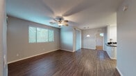 This single-floor residence offers a thoughtfully designed layout with a clean, neutral aesthetic throughout. The open living and dining area is finished with rich, dark hardwood-style flooring and features a ceiling fan, generous natural light from wide windows with blinds, and a pendant light that connects the space to the adjacent kitchen. Sliding glass doors provide outdoor access and bring additional natural light into the living area.

The kitchen is well-equipped with white shaker-style cabinetry, dark granite countertops, stainless steel appliances including a range and over-the-range microwave, and a peninsula with a double sink and built-in dishwasher — ideal for both cooking and casual dining.

The bedrooms are carpeted for comfort and each includes a ceiling fan and window with natural light. One bedroom offers direct outdoor access via a sliding glass door. The primary bath features a wide vanity with ample counter space, a large mirror, and an arched walk-in closet with shelving. A second full bathroom includes a white vanity and a tub-shower combination.

A dedicated laundry room houses a full-size washer and dryer with overhead shelving. Consistent grey-toned walls and white trim unify the interior, creating a bright and cohesive living environment throughout the home.
