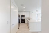 Located at 46 Soldiers Field Place in Boston, MA, this modern 2-bedroom, 2-bathroom residence offers a thoughtfully designed single-level floor plan. The open-concept living, dining, and kitchen area serves as the heart of the home, finished with light wood-style flooring that runs throughout. The kitchen is outfitted with crisp white cabinetry extending to the ceiling, stone-look quartz countertops, a peninsula with an undermount sink, and a full suite of stainless steel appliances including a refrigerator, range, microwave, and wall oven. Pendant lighting adds a polished touch above the peninsula. The living and dining area benefits from abundant natural light and direct access to a private balcony with open outdoor views of the surrounding greenery. Both bedrooms are bright and airy, featuring large windows with scenic views, light flooring, and generous closet space. The primary bedroom includes balcony access. The bathrooms are finished with dark tile flooring, white subway tile tub surrounds, and modern vanities with white countertops. An in-unit laundry area and three closets add practical convenience throughout this clean, contemporary residence.