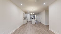 This well-appointed single-floor home offers a clean, modern aesthetic throughout, characterized by a neutral color palette, crisp white trim, and light hardwood-style flooring that flows seamlessly across the main living areas. The open-concept kitchen serves as the centerpiece of the home, showcasing a central island with granite countertops, gray shaker-style cabinetry, and a full suite of stainless steel appliances including a range, microwave, and French door refrigerator. An elegant chandelier overhead adds a refined touch to the space. The spacious living area features a ceiling fan, recessed lighting, and windows that invite natural light, creating a welcoming atmosphere. Bedrooms are finished with plush carpet and feature windows fitted with blinds for privacy and light control. The primary bathroom offers a dual-sink vanity with granite countertops and brushed nickel fixtures, complemented by a soaking tub. A secondary bathroom provides a full tub-shower combo with matching granite vanity details and brushed nickel hardware. Throughout the home, clean lines, recessed lighting, and consistent finishes contribute to a cohesive, move-in-ready environment that balances comfort and modern style.