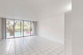 Located in Coral Springs, Florida, this well-appointed 2-bedroom, 2-bathroom residence offers a clean, bright, and efficiently designed single-floor layout. White square tile flooring runs throughout the entire space, creating a cohesive and easy-to-maintain interior that reflects Florida's sunny climate.

The open-plan combined dining and living area is generously sized, bathed in natural light from floor-to-ceiling sliding glass doors that lead directly to a private balcony. The balcony overlooks a pool area framed by mature trees, offering a pleasant outdoor retreat. A textured ceiling adds a subtle design detail to the living space.

The kitchen features white cabinetry, granite-style countertops, stainless steel appliances including a range, dishwasher, and refrigerator, as well as a skylight that enhances natural brightness. A dedicated laundry area with a full-size washer and dryer adds everyday convenience.

The primary bedroom is spacious and well-lit, benefiting from large windows with outdoor views and an expansive wall of sliding closet doors offering generous storage. A second bedroom provides additional flexible living space. Both bathrooms are finished with white tile, including a full tub-shower combination. Four closets throughout the unit ensure ample storage. The entrance hallway connects all areas of the home in a practical and organized flow.