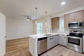 Located at Skyview 331 in Lynnwood, Washington, this single-floor residence showcases a cohesive contemporary design with light wood-tone flooring running consistently throughout the entire space. The open-concept kitchen serves as the central highlight, featuring a peninsula with a white quartz countertop, an undermount sink with a professional-style pull-down faucet, and a full suite of stainless steel appliances including a range, microwave, dishwasher, and refrigerator. Two-toned cabinetry pairs light gray lower cabinets with warm wood-finish upper cabinets, complemented by a classic subway tile backsplash. Pendant lights with globe bulbs hang above the peninsula, while recessed lighting and a ceiling fan illuminate the adjacent living area, which receives natural light through multiple windows with horizontal blinds.

The bedrooms are bright and well-proportioned, with ceiling fans, large windows offering views of surrounding greenery, and sliding-door closets equipped with built-in shelving and hanging rods. The bathrooms maintain the same modern palette, featuring gray vanity cabinets with matte black hardware, white quartz countertops, large mirrors, and light wood-look tile flooring. The overall ambiance is clean, minimalist, and move-in ready.