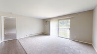 Located at 14 Meadow Dr in Milford, Ohio, this single-floor, one-bedroom, two-bathroom residence offers a well-organized and functional layout. The living room is a generously sized, light-filled space featuring soft carpeting, neutral warm-toned walls, and a large sliding glass door fitted with vertical blinds that opens to an outdoor view of lush greenery — allowing ample natural light to fill the room. A baseboard heating unit and wall-mounted air conditioning unit ensure year-round comfort.

The spacious primary bedroom continues the carpeted flooring and neutral palette, featuring a wide sliding window that frames outdoor views and a baseboard heater beneath it. The kitchen is efficiently designed with warm wood cabinetry, light stone-look countertops, and stainless steel appliances including a full-size refrigerator, complemented by durable wood-look flooring. The dining room provides a dedicated space adjacent to the kitchen area.

The two bathrooms are clean and functional. One features a full tub-shower combo with white tile surround, wood-look flooring, and standard fixtures, while the other includes a wood-cabinet vanity with a white sink and floor-to-ceiling storage closet. Throughout the home, a consistent neutral color scheme and wood-look hard flooring in key areas create a cohesive and tidy aesthetic.