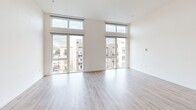 This three-bedroom, two-bathroom unit at 1517 H Street in downtown Sacramento offers a well-designed single-level layout with a thoughtful blend of modern aesthetics and functional living spaces. Light-toned hardwood-style flooring flows throughout the open-concept kitchen and living area, while plush carpet adds comfort to the bedrooms.

The kitchen is outfitted with stainless steel appliances, including a French door refrigerator, electric range, over-the-range microwave, and dishwasher. Two-toned cabinetry pairs white high-gloss upper cabinets with warm wood-grain lower cabinets, complemented by a marble-style tile backsplash and light quartz countertops.

The living area is a standout, featuring soaring ceilings and expansive floor-to-ceiling windows with transom panels that flood the space with natural light and offer open views of the surrounding Sacramento cityscape. The primary bedroom continues this window-forward design with corner glass panels and a sliding-door closet with built-in shelving.

Both bathrooms feature tub-shower combinations with elegant marble-style surround walls, chrome fixtures, and hardwood-style flooring. A dedicated hallway closet provides additional storage, completing this contemporary urban residence.