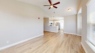 This two-story home in D'Iberville, Mississippi offers a well-organized layout across two floors, with the main living spaces on the ground level and the bedrooms situated above. The open-concept kitchen and living room serve as the heart of the home, featuring light wood-look flooring, warm neutral tones, and multiple windows dressed with white blinds that allow natural light to fill the space. The living area is anchored by a fireplace and topped with soaring vaulted ceilings, with a ceiling fan adding both style and function. The upper floor hosts three bedrooms, each finished with plush carpet and ceiling fans. The generously sized primary bedroom includes a walk-in closet with built-in wire shelving. The two bathrooms are clean and functional, with the full bath featuring a tub-shower combo, white cabinetry, and light wood-look flooring. A dedicated laundry room on the upper level includes wire shelving, washer and dryer hookups, and an electrical panel. The ground floor includes an attached garage with a roll-up door, offering ample storage or parking. Hallways connect the spaces efficiently, completing this practical and comfortable home.