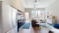 Located in the heart of downtown Columbus at 150 N 3rd St, this modern studio offers a thoughtfully designed open-concept layout that seamlessly blends living, sleeping, and cooking areas into one cohesive space. Rich hardwood flooring runs throughout, anchoring the warm yet contemporary aesthetic.

The kitchen is a standout feature, showcasing dark cabinetry paired with crisp white quartz countertops, a classic white subway tile backsplash, stainless steel appliances including a gas range and French door refrigerator, and open wood shelving that adds both function and visual warmth.

The living and sleeping area is generously proportioned, bathed in natural light from large floor-to-ceiling windows that frame impressive views of the Columbus skyline. Soaring ceilings with exposed industrial ductwork and a ceiling fan lend the space a loft-like character. A ceiling track lighting system provides flexible illumination throughout.

The bathroom is clean and modern, featuring a walk-in shower with tile surround and warm hardwood-style flooring. An exterior door provides access to an outdoor area, further enhancing the connection to the vibrant urban surroundings. This unit captures the energy of downtown Columbus living with a polished, contemporary interior design.