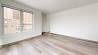 Located at 2132 Stokes Blvd in Cleveland's vibrant University Circle area, this well-appointed 2-bedroom, 2-bathroom residence offers a thoughtfully designed single-floor layout with a clean, contemporary aesthetic throughout. Light-toned luxury vinyl plank flooring runs continuously through every room, complementing the crisp white walls and creating a bright, cohesive feel.

The open-concept kitchen and living area serves as the heart of the unit. The kitchen is outfitted with sleek grey cabinetry, white quartz countertops, a subway tile backsplash, stainless steel appliances including a refrigerator, range, and built-in microwave, and a large center island with pendant lighting. Oversized windows flood the space with natural light and frame views of the surrounding Cleveland cityscape.

The primary bedroom is a generously sized retreat featuring dual large windows that bring in additional natural light and city views, along with a double-door closet offering ample storage. The second bedroom is bright and well-proportioned with its own closet access. Three total closets are distributed throughout the unit for added convenience.

Both bathrooms carry the modern design language forward, featuring grey floating vanities with white countertops, matte black fixtures, large mirrors, and wood-toned LVP flooring. The primary bath includes a glass-enclosed walk-in shower. An in-unit laundry area completes this functional and stylish residence.