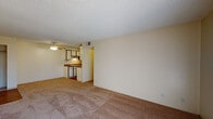 Located at 4404 Montebello Dr in Colorado Springs, CO, this single-story unit offers a straightforward, functional layout suited for comfortable everyday living. The living area is generously sized, featuring warm beige carpet, neutral-toned walls, a textured ceiling, and a ceiling fan. A sliding glass door leads to an outdoor balcony, allowing natural light to fill the space and providing views of the surrounding greenery.

The galley-style kitchen is efficiently designed with white cabinetry lining both walls, brown laminate countertops, a double-basin sink, a white refrigerator, an electric range, and a dishwasher. Wood-style flooring runs through the kitchen, adding a warm contrast to the cabinetry.

The bedrooms are carpeted and feature neutral walls with textured ceilings. One bedroom includes a window overlooking outdoor greenery, while another offers a closet with built-in shelving. Additional closet space is present throughout.

The bathroom includes a tub-shower combination with tile surround, a vanity with under-sink storage, a framed mirror, and a multi-bulb light fixture above. Wood-style flooring continues in this space, complementing the clean, neutral finishes found throughout the unit.