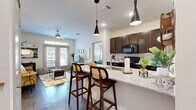 Located in San Antonio, TX, this thoughtfully designed 2-bedroom, 2-bathroom residence offers a seamless blend of comfort and modern style across a single floor. The open-concept kitchen and living area serves as the heart of the home, where rich dark-wood cabinetry, granite countertops, a herringbone tile backsplash, and a spacious island with bar seating create an inviting and functional space. Sleek pendant lighting and wood-style flooring flow throughout, adding warmth and visual continuity. The living room benefits from large windows and a glass-panel door that invite generous natural light and provide outdoor access. A ceiling fan adds comfort to the space. The kitchen features black appliances and ample cabinet storage. Both bedrooms are well-proportioned, with the primary offering an en-suite bathroom complete with a glass-enclosed shower, dark vanity cabinetry, and granite countertops. The secondary bathroom features a tiled soaking tub and shower combination with a similarly styled vanity. Bedrooms are served by multiple closets, providing excellent storage. A dedicated laundry area adds everyday convenience. The overall ambiance is bright, clean, and modern, making this residence a comfortable and stylish home.
