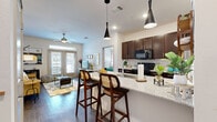 Located in San Antonio, TX, this thoughtfully designed 2-bedroom, 2-bathroom residence offers a seamless blend of comfort and modern style across a single floor. The open-concept kitchen and living area serves as the heart of the home, where rich dark-wood cabinetry, granite countertops, a herringbone tile backsplash, and a spacious island with bar seating create an inviting and functional space. Sleek pendant lighting and wood-style flooring flow throughout, adding warmth and visual continuity. The living room benefits from large windows and a glass-panel door that invite generous natural light and provide outdoor access. A ceiling fan adds comfort to the space. The kitchen features black appliances and ample cabinet storage. Both bedrooms are well-proportioned, with the primary offering an en-suite bathroom complete with a glass-enclosed shower, dark vanity cabinetry, and granite countertops. The secondary bathroom features a tiled soaking tub and shower combination with a similarly styled vanity. Bedrooms are served by multiple closets, providing excellent storage. A dedicated laundry area adds everyday convenience. The overall ambiance is bright, clean, and modern, making this residence a comfortable and stylish home.