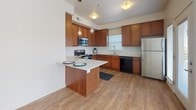 This single-story residence is designed with a practical and cohesive layout, offering a comfortable living environment across several well-defined spaces. The kitchen serves as a central highlight, featuring rich medium-toned wood cabinetry with brushed nickel hardware, light quartz countertops, and a full suite of stainless steel appliances including a range, over-the-range microwave, refrigerator, and dishwasher. A peninsula island provides additional counter space and casual seating, while pendant lighting and wood-look flooring complete the functional yet stylish design.

The bedrooms are carpeted in neutral tones and receive generous natural light through sets of triple windows fitted with horizontal blinds. The rooms offer a clean, open feel with crisp white walls and structured ceiling details.

The bathrooms maintain the same warm aesthetic found throughout the unit, showcasing rich wood vanities with light countertops, large mirrors, and tile flooring. One bathroom includes a bathtub and shower combination, while another features a single vanity with access to a walk-in closet area. Together, the spaces present a consistent, well-finished interior suited for everyday living.