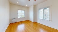 Located at 463 Hartford Ave, Unit 211, in Los Angeles, CA, this efficiently designed single-floor unit offers a well-organized layout comprising a living room, kitchen, bathroom, hallway, and closet. The living room serves as the heart of the space, featuring warm hardwood flooring, crisp white walls, and two windows with horizontal blinds that invite generous natural light and offer views of the surrounding neighborhood. A ceiling fan adds both function and a finishing touch to the bright, airy atmosphere. The kitchen is thoughtfully appointed with warm wood cabinetry, granite-style countertops, a gas range, refrigerator, and a sink beneath a window — all set on clean tile flooring that contrasts nicely with the living area. The bathroom continues the tile flooring and includes a wood-framed vanity with an under-cabinet basin, a wall mirror, and a separate tub/shower enclosure clad in elegant beige tile. The hallway connects the rooms efficiently, with a dedicated closet providing practical storage. The entry area features clean white walls and hardwood flooring consistent with the rest of the unit. Overall, the space maintains a clean, neutral aesthetic with warm wood tones and ample natural light throughout.