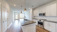 Located at 203 Eleanor Way in Murfreesboro, Tennessee, this well-appointed single-story home offers three bedrooms, two bathrooms, a dedicated closet, and a connecting hallway — all finished with consistent hardwood-style flooring and a clean, neutral color palette throughout.

The kitchen serves as the centerpiece of the home, featuring white shaker-style cabinetry, a white subway tile backsplash, dark quartz countertops, stainless steel appliances including a range, microwave, and refrigerator, and a large center island with a built-in sink and pendant lighting. The open layout connects seamlessly to the living area, enhancing the sense of spaciousness.

Each bedroom is bright and airy, benefiting from large windows that invite natural light and offer views of the surrounding neighborhood. Ceiling fans are installed in every bedroom for added comfort. Crown molding adds a refined architectural detail throughout the living spaces.

The primary bathroom is outfitted with a dual-sink vanity, dark quartz countertops, white cabinetry, framed mirrors, and a glass-door shower. The secondary bathroom features a classic white subway tile tub-and-shower surround. Together, the bathrooms reflect a cohesive, modern aesthetic that complements the rest of the home.