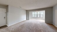 Located on Mercer University Drive in Macon, Georgia, this single-story unit offers a practical and functional layout across a comfortable footprint. The combined kitchen and living room forms the heart of the space, with the living area featuring wall-to-wall carpeting, neutral gray walls, and a textured ceiling. A large front-facing window with vertical blinds allows natural light to fill the room, enhancing its open feel. A ceiling fan with integrated lighting provides both comfort and illumination.

The kitchen is laid out in a galley style, featuring wood-trimmed white cabinetry, speckled countertops, and wood-look vinyl flooring. Black appliances, including a refrigerator and dishwasher, are already in place, and the kitchen opens directly into the living area for easy flow.

The bedroom is generously sized, outfitted with carpet, a ceiling fan with light fixture, and a window that brings in natural light. A dedicated closet provides ample storage. Neutral tones throughout maintain a clean, cohesive aesthetic.

A separate laundry room includes washer and dryer hookups, overhead cabinetry for storage, and both 110V and 220V outlets, offering full in-unit laundry capability. The overall layout is efficient and well-organized, making excellent use of the available space.