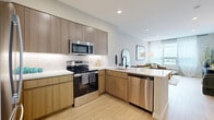 This well-appointed one-bedroom, one-bathroom residence at 74 Freeman Street in Newark, NJ offers a thoughtfully designed open-concept layout with modern finishes throughout. Light wood-tone flooring runs continuously across the space, creating a cohesive and airy feel from entry to living area.

The kitchen is a standout feature, equipped with stainless steel GE appliances including a range, built-in microwave, dishwasher, and French door refrigerator. Flat-front wood-grain cabinetry is paired with crisp white quartz countertops and a subway tile backsplash, while an L-shaped peninsula provides both prep space and a natural transition into the living area.

The living room benefits from large windows dressed with sheer curtains, allowing generous natural light and offering open outdoor views of the surrounding neighborhood. The bedroom is a comfortable, well-proportioned retreat, also featuring a window with exterior views, light flooring, and ample room for a full furniture arrangement. A dedicated closet provides convenient storage.

The bathroom is finished with large-format neutral tile flooring, a dark-toned vanity with a white countertop, a framed mirror, and a shower-tub combination with white subway tile surround. Clean lines and neutral tones define the overall aesthetic of this contemporary Newark residence.