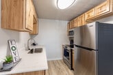 Located at 543 S Curtis Rd in Boise, Idaho, this single-level 2-bedroom unit offers a clean, functional layout with consistent light hardwood-style flooring running throughout every room, creating a cohesive and easy-to-maintain living environment.

The living area is well-proportioned and filled with natural light through a large window fitted with horizontal blinds. A ceiling fan with a built-in light fixture provides both comfort and illumination. The space also features a large double-door closet, adding notable storage capacity to the main living area.

The kitchen is efficiently designed with warm-toned natural wood cabinetry extending to upper and lower sections, white countertops, a stainless steel sink, dishwasher, and refrigerator. Sunlight reflects off the flooring, keeping the kitchen feeling bright and welcoming.

Both bedrooms are comfortably sized, each featuring a window with blinds, baseboard heating, and a ceiling fan. One bedroom includes a double-door closet with ample storage. The neutral wall tones in each room create a calm, versatile atmosphere.

The bathroom features a white vanity with a large mirror, white countertop with under-sink storage, and a shower-tub combination. The hardwood-style flooring extends into the bathroom, maintaining design continuity throughout the unit.