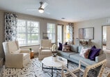 Located in Bonita Springs, FL, this well-appointed 2-bedroom, 2-bathroom residence offers a thoughtfully designed single-level floor plan with a comfortable, modern aesthetic throughout. The open-concept living and dining area is bright and welcoming, featuring multiple large windows that flood the space with natural light, elegant patterned drapery, and a ceiling fan overhead. Wood-look flooring anchors the common areas, creating a warm and cohesive feel. The kitchen is a standout feature, showcasing crisp white shaker-style cabinetry, dark countertops, stainless steel appliances including a range, microwave, and refrigerator, and track lighting — all complemented by the same wood-look flooring. The primary bedroom offers a generous footprint with plush carpeting, a ceiling fan, and access to a walk-in closet with built-in shelving. The second bedroom is equally comfortable, also carpeted and bright. Both bathrooms are finished with single-sink vanities, dark countertops, and tub-shower combinations with tile surrounds. Additional highlights include multiple closets for storage, a dedicated laundry area, hallways connecting the private spaces, and a patio for outdoor enjoyment. The overall ambiance is clean, neutral, and move-in ready.