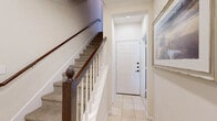 This two-story home offers four bedrooms, three bathrooms, and a thoughtfully organized layout spread across two levels. The majority of the living space is situated on the upper floor, while the lower level provides a functional entry point into the home.

The entryway welcomes residents with light tile flooring and a classic staircase featuring a dark wood banister with white balusters and carpeted treads. The living room showcases elevated ceilings, rich hardwood flooring, arched architectural details, and a tile-surround fireplace, creating an open and elegant atmosphere.

The combined kitchen and dining area is well-equipped with rich dark wood cabinetry, granite countertops, stainless steel appliances, and tile flooring. The dining space features hardwood floors, natural light from large windows, and access to an outdoor area.

The primary bedroom is generously sized with plush carpeting, crown molding, a ceiling fan, and natural light. It is accompanied by a spacious walk-in closet with built-in shelving and hanging rods. Additional bedrooms are carpeted and feature crown molding and ceiling fans.

The bathrooms include granite-topped vanities with wood cabinetry and tile flooring. Three closets and four hallways contribute to the home's practical and organized flow throughout.