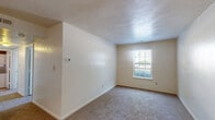 Located at 401 Rivers Post Ct in Virginia Beach, Virginia, this single-floor, two-bedroom, one-bathroom residence offers a practical and functional layout. The kitchen is efficiently designed with warm-toned wood cabinetry, dark granite-style countertops, tile flooring, and a full suite of white appliances including a coil-top range, over-the-range microwave, and a full-size refrigerator. A pass-through counter connects the kitchen to the living area, creating an open and communicative flow between the two spaces. The living area features neutral carpet flooring and clean white walls, providing a versatile backdrop. Both bedrooms are carpeted and finished with neutral tones, offering a calm and quiet atmosphere. Each bedroom benefits from natural light through windows with blinds, and the primary bedroom includes a double-door closet for ample storage. The shared full bathroom is well-appointed with a wood-vanity, a white countertop, a large mirror, tile flooring, and a full tub-shower combination. A hallway connects the main living areas seamlessly. Throughout the residence, consistent neutral paint tones and clean finishes contribute to a cohesive, move-in ready aesthetic.