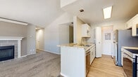 Located at 27701 Detroit Road in Westlake, Ohio, this two-bedroom, one-bathroom residence offers a thoughtfully laid-out single-floor plan. The living room immediately impresses with soaring vaulted ceilings and multiple windows that flood the space with natural light. A tiled fireplace serves as a focal point, adding warmth and character to the room, which features neutral carpet throughout.

The kitchen is designed for efficiency, featuring a galley-style layout with white cabinetry, granite-style countertops, stainless steel appliances including a range, microwave, and refrigerator, and a peninsula that opens toward the living area. Light hardwood-style flooring runs through the kitchen, enhancing its clean, bright aesthetic.

Both bedrooms are carpeted and offer a comfortable, quiet retreat. The primary bedroom includes a ceiling fan and a window for natural light, while the second bedroom provides closet access and easy hallway connectivity. The full bathroom features a tiled tub-shower combination with a distinctive red accent tile border.

A dedicated laundry area with an in-unit washer and overhead shelving adds practical convenience. The entrance provides a smooth transition into the open living spaces, completing this well-organized and functional home.