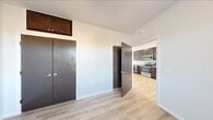 This single-floor residence at 21 Village Circle offers a clean, contemporary design highlighted by light-toned hardwood flooring that runs consistently throughout the unit. The kitchen serves as a functional centerpiece, featuring rich dark-brown shaker-style cabinetry extending to the ceiling for generous storage, granite-look countertops, and a full suite of stainless steel appliances including a refrigerator, electric range, microwave, and dishwasher. A tall pantry cabinet provides additional storage, while a nearby window brings in natural light.

The living and sleeping areas are bright and open, with large windows inviting abundant natural light and views of the surrounding neighborhood. Wall-mounted mini-split units provide individual climate control, and ceiling fans are present in select rooms for added comfort. Bedroom spaces include double-door closets with overhead cabinetry for maximized storage.

The bathroom is well-equipped with dark wood vanity cabinetry, a single-sink vanity with a light countertop, a tub-shower combination with sliding glass doors, and a tall linen cabinet. White walls and clean lines throughout the unit create a cohesive, modern aesthetic that is both practical and inviting.