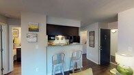 Located at 4500 E 82nd St in Indianapolis, IN, this single-floor residential unit offers a well-designed layout with a cohesive modern aesthetic throughout. The kitchen is a standout feature, boasting granite countertops, dark espresso cabinetry, hardwood-style flooring, and black appliances. A galley-style configuration maximizes counter space on both sides, while a dedicated pantry provides generous storage. The kitchen opens to a breakfast bar with seating, creating a natural transition into the living area. The living room is bright and welcoming, with a large window that draws in natural light and provides a comfortable, open atmosphere. The bedroom offers plush carpeting, ample dresser space, and a sliding glass door that opens to an outdoor area, filling the room with additional natural light and outdoor connectivity. A second bedroom features soft carpeting and warm ambient lighting. The bathroom is clean and functional, with a dark vanity cabinet, white countertop, a well-lit mirror, and modern brushed nickel fixtures. A laundry area is conveniently accessible within the unit. Throughout the space, hardwood-style flooring in the main areas and soft carpet in the bedrooms provide both durability and comfort, contributing to a cohesive and inviting living environment.