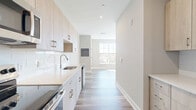 Located at 219 Ash Creek Boulevard in Fairfield, CT, this thoughtfully designed one-bedroom, one-bathroom residence offers a clean, modern aesthetic throughout its efficiently organized single-floor layout. Light wood-tone flooring flows seamlessly from room to room, complemented by crisp white walls and abundant recessed lighting that create a bright, welcoming atmosphere.

The galley-style kitchen is a standout feature, outfitted with light natural wood cabinetry extending to the ceiling, gleaming white quartz countertops, white subway tile backsplash, and a full suite of stainless steel appliances including a refrigerator, electric range, microwave, and dishwasher. The kitchen opens naturally toward the living area, which benefits from large windows that invite generous natural light.

The bedroom is a cozy, well-proportioned retreat with warm hardwood-style flooring and a large multi-pane window framing pleasant outdoor views. Two closets provide practical storage throughout the unit, and an in-unit laundry adds everyday convenience.

The bathroom is elegantly appointed with a light wood vanity, white quartz countertop, large frameless mirror, and a full soaking tub with a striking marble-style tile surround. Neutral large-format floor tiles complete the polished look. The overall ambiance is fresh, modern, and move-in ready.