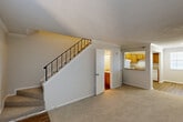 This two-story home in Metairie, Louisiana offers three bedrooms and two bathrooms across two well-organized floors. The main level welcomes you through a front entry with a large window that fills the living room with natural light. Soft carpet extends throughout the living area, which flows seamlessly toward a pass-through kitchen featuring warm oak cabinetry, hardwood-style flooring, a full suite of white appliances including a refrigerator, range, and dishwasher, and a countertop bar opening to the living space. A staircase with a black metal railing connects the floors, and a full bathroom is conveniently located on the main level. Upstairs, the three bedrooms are carpeted and finished in neutral tones, offering a calm and functional atmosphere. The generously sized primary bedroom provides ample space for furnishings. Additional bedrooms are well-proportioned and served by a hallway with hardwood-style flooring. Each bathroom features wooden vanity cabinetry with light countertops. Textured ceilings and crown molding add a finishing touch throughout, while ceiling fans in the bedrooms ensure year-round comfort. The layout is efficient and practical, making this Metairie home a comfortable and well-appointed residence.