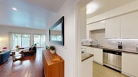 Located on Thayer Avenue in the heart of West Los Angeles, this thoughtfully designed 2-bedroom, 2-bathroom residence offers a comfortable and stylish single-level layout. Rich hardwood floors flow throughout the main living areas, anchoring a bright and open living room with recessed lighting and large sliding glass doors that invite natural light and provide direct access to a private balcony. The adjacent dining area transitions seamlessly into a modern kitchen featuring glossy white cabinetry, a subway tile backsplash, stone countertops, stainless steel appliances including a gas range and dishwasher, and light tile flooring—a clean, functional space well-suited for everyday cooking and entertaining. A welcoming hallway with a wall-mounted mirror and wood console connects the public and private areas of the home. The generously sized primary bedroom offers hardwood floors, recessed lighting, a mirrored closet, and a dedicated en-suite bath. A second bedroom provides ample space with its own closet and mirrored sliding doors. Both bathrooms are finished with floating vanities, warm countertops, and tiled walls for a cohesive, contemporary aesthetic. Three closets throughout the home ensure abundant storage. The overall ambiance is clean, modern, and inviting.