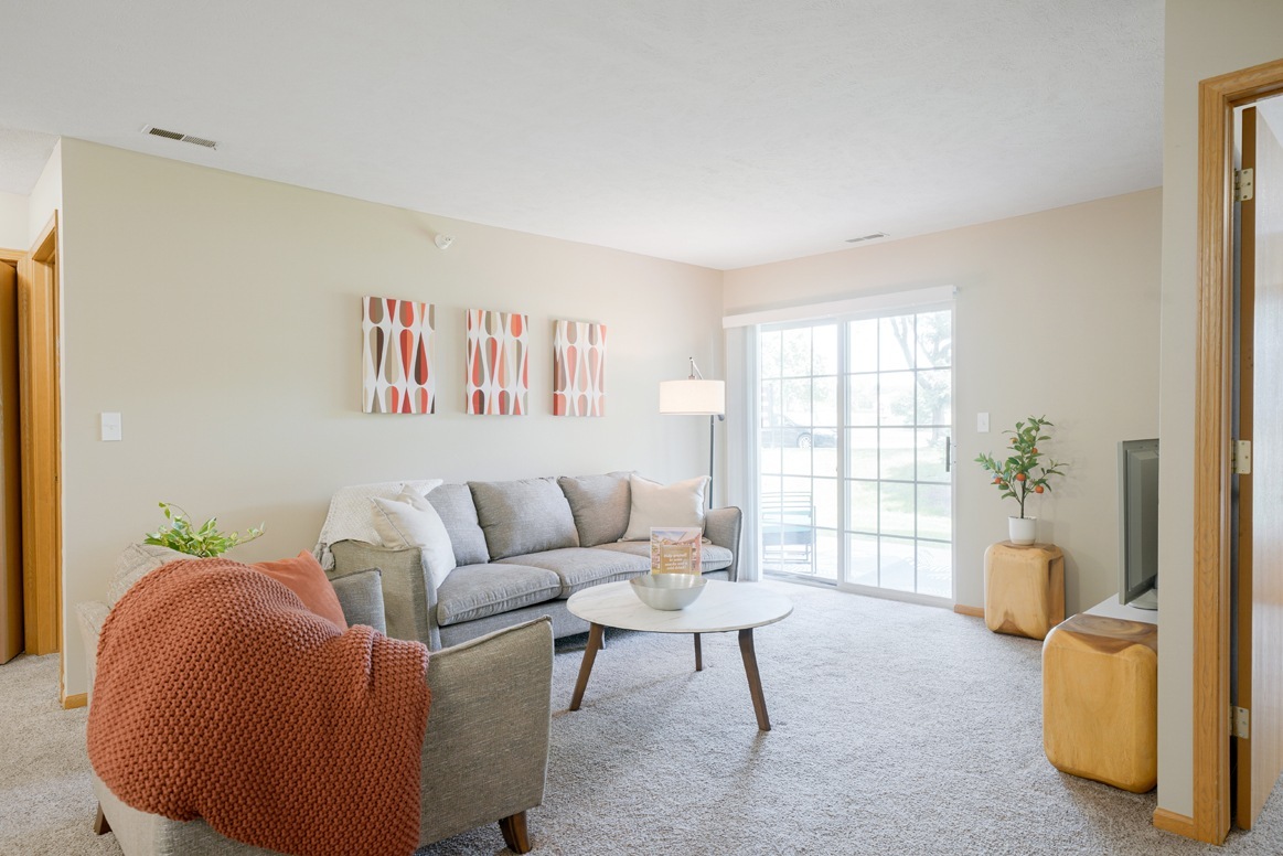 Our bright and cozy living rooms feature large sliding doors, inviting natural light and seamless indoor-outdoor living. - Williamsburg Park Apartments