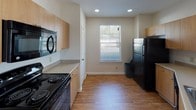 This single-floor residence offers a thoughtfully designed layout with a seamless blend of comfort and functionality. The open-concept living and dining area is a standout feature, finished with warm hardwood-style flooring that extends throughout the main areas. A ceiling fan overhead and multiple windows with blinds allow for excellent natural light and airflow, while French doors provide outdoor access and further brighten the space.

The kitchen is efficiently arranged with light wood cabinetry, neutral countertops, recessed lighting, and black appliances including a range, microwave, and refrigerator. A breakfast bar connects the kitchen to the main living area, reinforcing the open flow of the floor plan.

The bedrooms are carpeted and generously sized, each featuring a ceiling fan, a window with natural views, and ample room for furnishings. One bedroom includes access to a spacious walk-in closet outfitted with wire shelving for organized storage.

Two full bathrooms serve the residence. One features a double-sink vanity with a wide mirror, neutral countertops, white cabinetry, and hardwood-style flooring. The second bathroom mirrors this clean aesthetic and includes a walk-in shower with glass doors. Both bathrooms offer a bright, functional design with consistent finishes throughout.